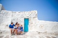 Family vacation in Europe. Parents and kids at street of typical greek traditional village with white walls and colorful Royalty Free Stock Photo