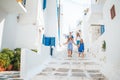 Family vacation in Europe. Parents and kids at street of typical greek traditional village with white walls and colorful Royalty Free Stock Photo