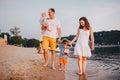 Family vacation in summer. Young Caucasian family foot walking barefoot sandy beach, shore river water. Dad mom holding hands two Royalty Free Stock Photo