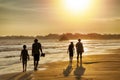 Family vacation in the tropics by the sea - silhouettes of people walking on the beach at sunset.