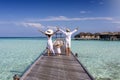 A family on vacation walks along a wooden pier in the Maldives