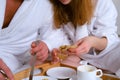 Young couple in bathrobes having a breakfast together in bed in hotel room. Royalty Free Stock Photo