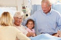 Family Visiting Senior Female Patient In Hospital Bed