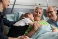 Family visiting sick retired senior woman in hospital ward Royalty Free Stock Photo