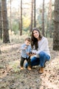 Family walk in the autumn forest. Attractive young mother and her little son playing together with pine cones, posing to Royalty Free Stock Photo