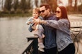 Family walk, father and mother hold daughter in their arms, family walks by the river, sunset, mother points with her hand Royalty Free Stock Photo