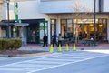 A family walking along a red brick sidewalk in a outdoor shopping center in front of the shops with yellow cones on the street