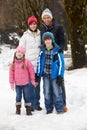 Family Walking Along Snowy Street In Ski Resort