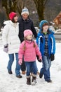 Family Walking Along Snowy Street In Ski Resort