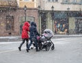 Family walking with the child in the stroller in snowy winter day Royalty Free Stock Photo