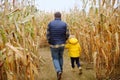 Family walking among the dried corn stalks in a corn maze. Little boy and his father having fun on pumpkin fair at autumn Royalty Free Stock Photo