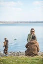 family walking near water. sitting at the beach. little kid throwing rock in water Royalty Free Stock Photo