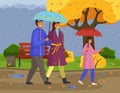 Family walking in the rain with umbrella and wearing raincoats in the city park in autumn season Royalty Free Stock Photo