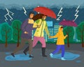 Family walking in the rain with umbrella and wearing raincoats in the city park in autumn season Royalty Free Stock Photo