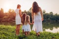 Family walking by summer river at sunset. Mother, grandmother and kids admiring landscape. Women`s day