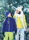 Family walking in winter day, happy mother and child son dressed in bright sportswear together over christmas tree