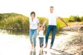 Family walks along the bank of the river in the evening, barefoot in the water and splashing Royalty Free Stock Photo