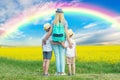 The family walks through the flowering field and look at the rainbow in the sky.