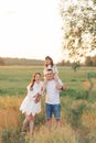 Family walks on meadow and father carries daughter on his shoulders Royalty Free Stock Photo