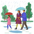 Daughter, dad and mom walking in park with umbrellas during the rain. Rainy weather outside, puddles Royalty Free Stock Photo