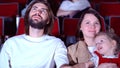 Family watching film in cinema. Media. Portrait of happy mom, dad, and cure little girl sitting together and watching an Royalty Free Stock Photo