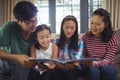 Family watching photo album together in living room