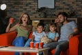 Family watching TV on sofa in evening