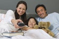 Family Watching TV Together In Bed