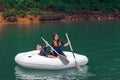 Siblings wearing life jackets paddling on an inflatable boat in Kenyir Lake, Malaysia Royalty Free Stock Photo