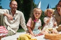 Family wearing party hats, celebrating kids birthday in the park on a summer day. Children having fun, blowing birthday Royalty Free Stock Photo