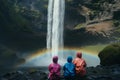 family wearing raincoats witnessing a waterfalls rainbow mist