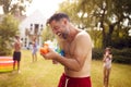 Family Wearing Swimming Costumes Having Water Fight With Water Pistols In Summer Garden