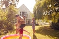 Family Wearing Swimming Costumes Having Water Fight With Water Pistols In Summer Garden