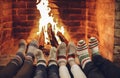 Family mother, father and kids wearing warm woolen socks warming feet by fireplace on Christmas time Royalty Free Stock Photo