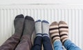 Family wears colorful pair of woolly socks warming cold feet in front of heating radiator in winter time. Royalty Free Stock Photo