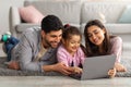 Family weekend. Cheerful arab parents teaching their little daughter using laptop, spending time at home together Royalty Free Stock Photo