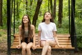 Family weekend, happy teenager girls sisters swing on a swing in the summer in the park Royalty Free Stock Photo