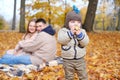 Family weekend. Young parents with their little son spend time together in the autumn park. The child eats an apple, the Royalty Free Stock Photo