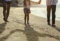 Family who enjoy a picnic. Parents are holding hands their children and walking on the beach at sunset in holiday. Royalty Free Stock Photo