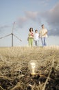 Family and wind turbines, light bulb in the ground Royalty Free Stock Photo