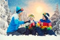 Mother and two sons drink hot tea in a snowy forest after sledging. Drink hot tea together.Family Winter fun for Christmas vacatio Royalty Free Stock Photo