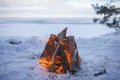Family winter picnic. Bonfire on the shore of a frozen lake during a winter travel Royalty Free Stock Photo