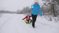 Family winter vacation. child and mother sledding in snow. Daughter and mom play in the winter park on Christmas