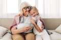 Girl winter hugging plaid granddaughter child mugs grandmother couch sofa Royalty Free Stock Photo