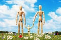A family of wooden mannequins on a lawn surrounded by flowers