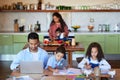 Family working at a kitchen table, doing homework at home. A young man using a laptop next to his children. A little boy Royalty Free Stock Photo