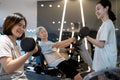 Family workout in the gym,smiling asian mother and daughter exercise with dumbbells,senior grandmother sit on the spinning bicycle Royalty Free Stock Photo