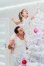 Family, x-mas, winter holidays and people concept - happy father and little daughter decorating christmas tree at home Royalty Free Stock Photo