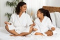 Family Yoga. Happy Black Mom And Daughter Wearing Bathrobes Meditating Together