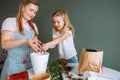 Family of young blonde woman and toddler girl transplant indoor plants at home. Mother and daughter spend time together Royalty Free Stock Photo